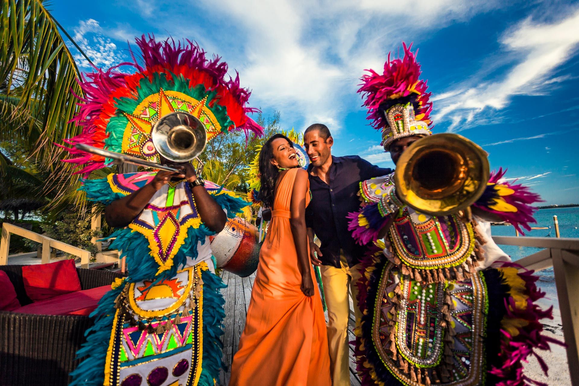 A couple dancing with Bahamian Junkanoo berformers