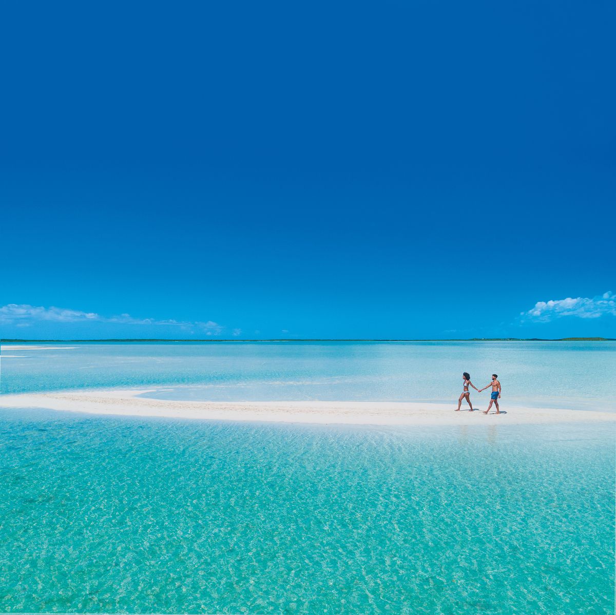 couple walking on a sandbar in the bahamas