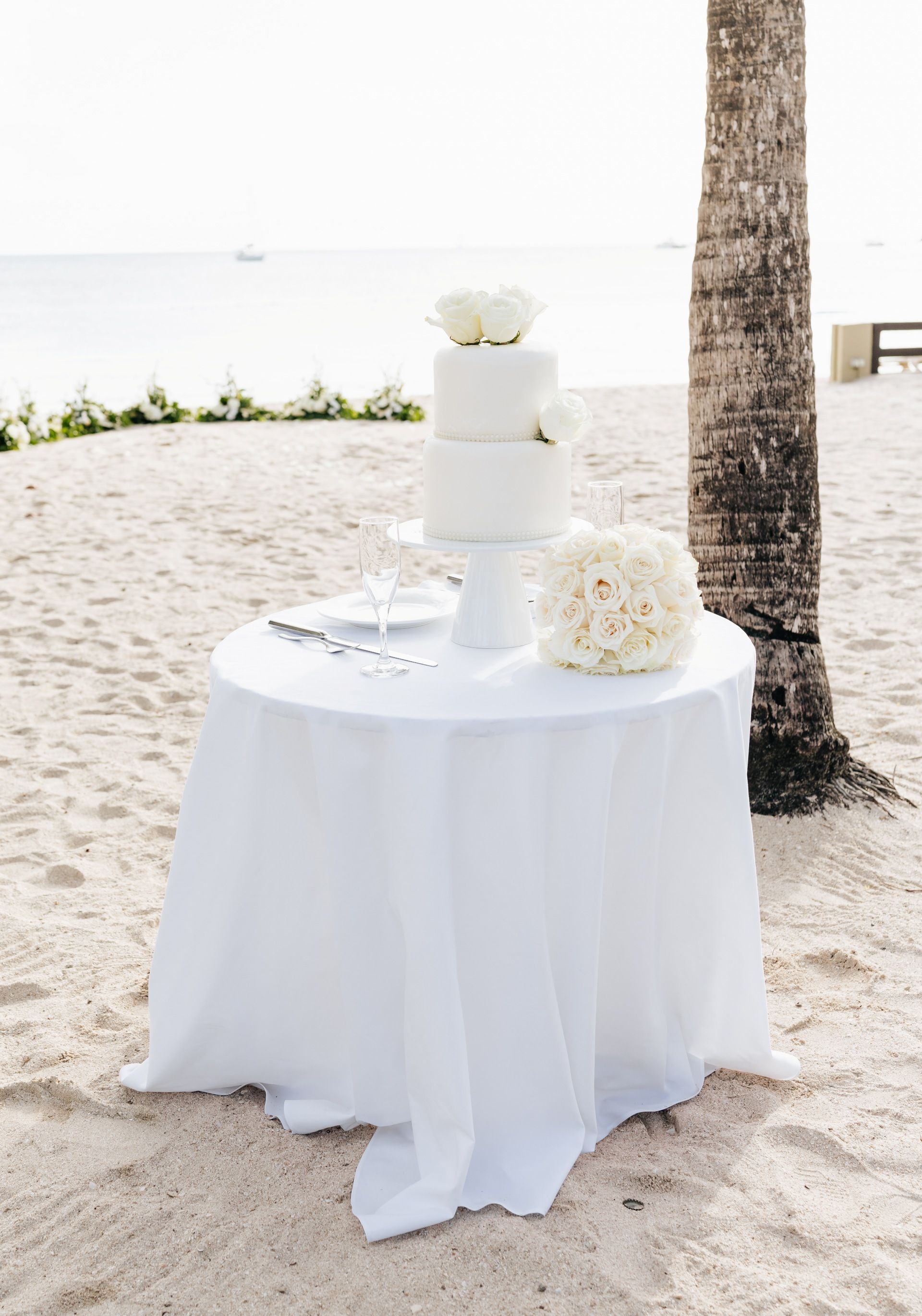 Simple white wedding cake set on the beach for an intimate elopement