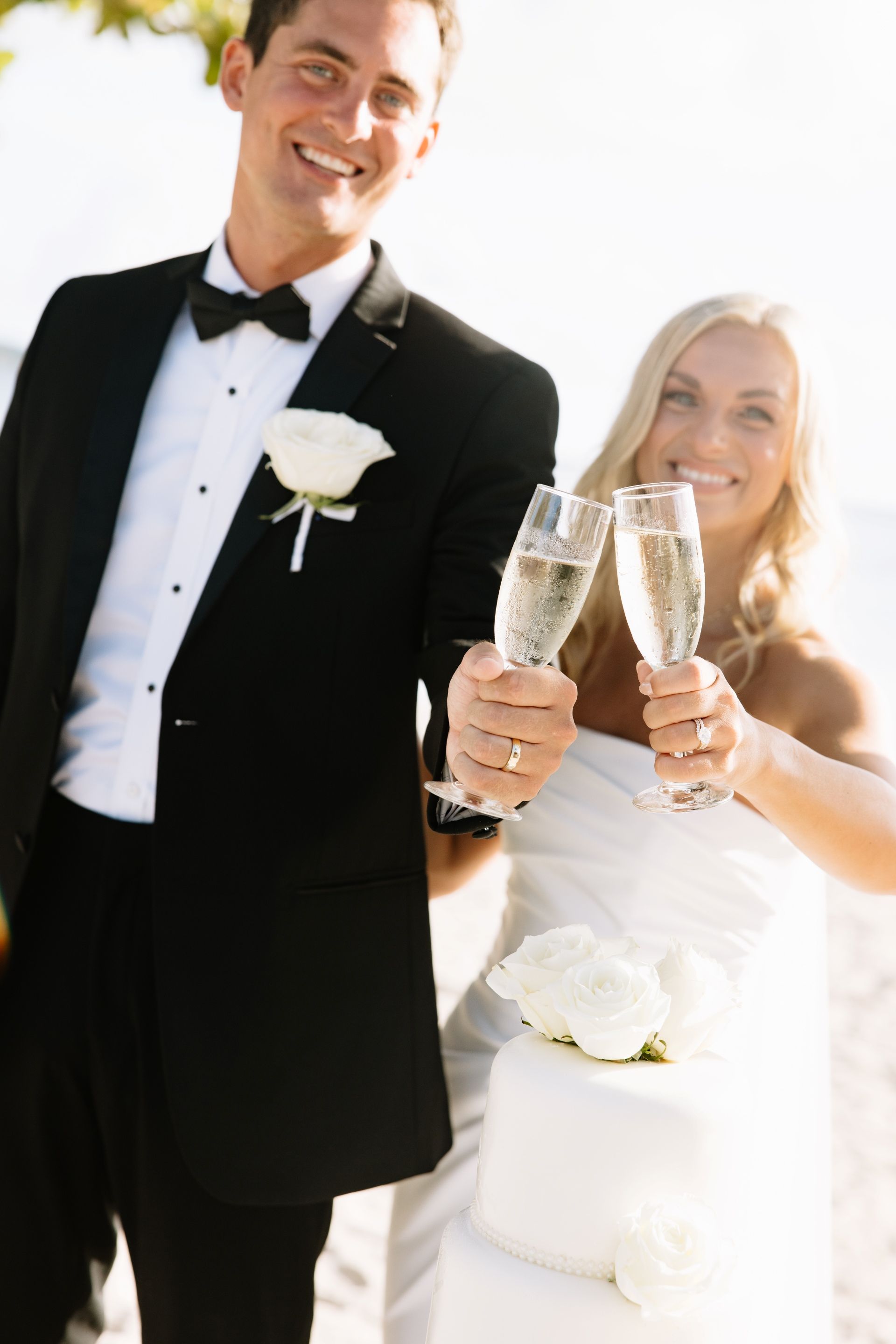 bride and groom toasting with champagne on the beach after their ceremony