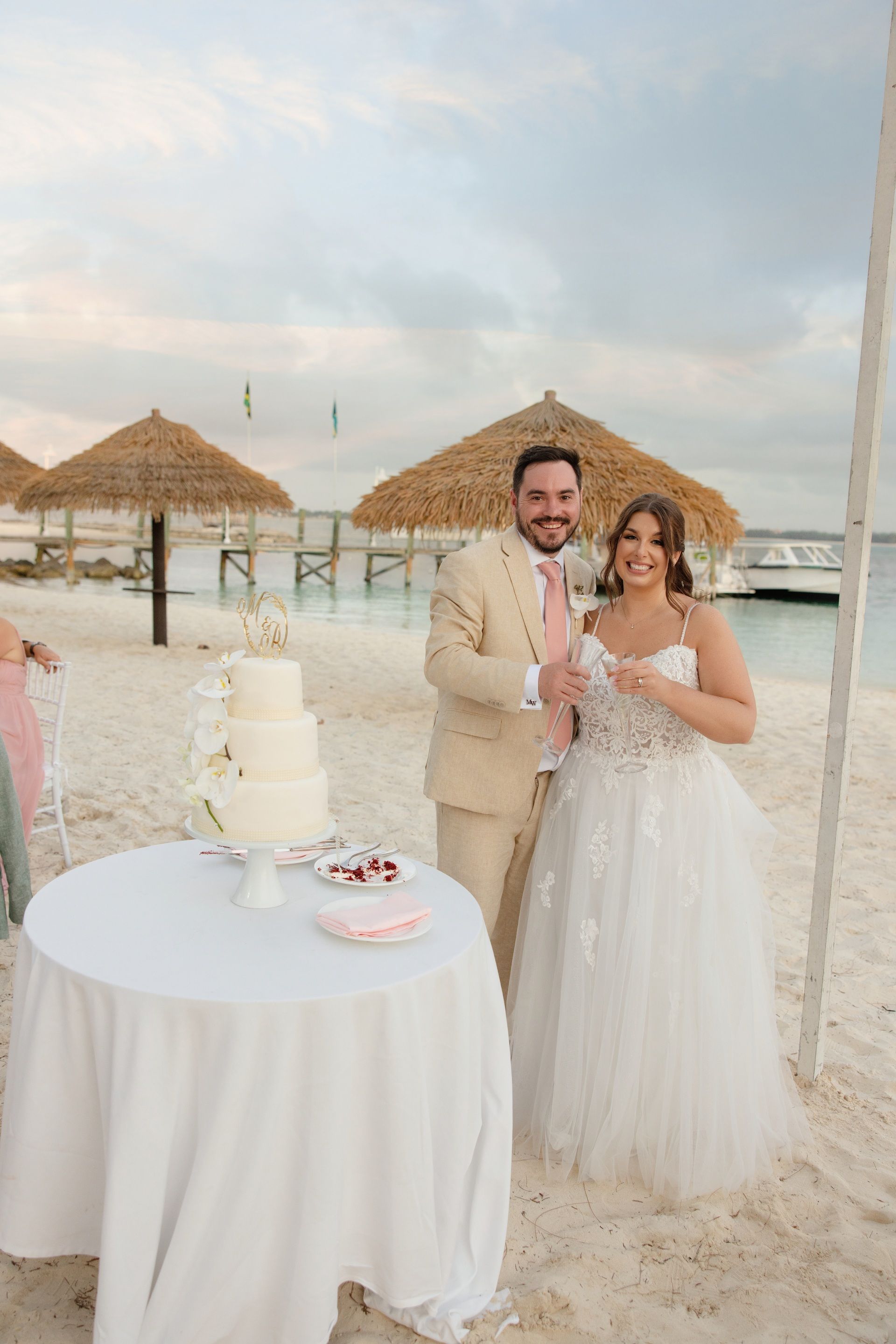 Bride and groom cutting cake on the beach under palapas at their Sandals wedding