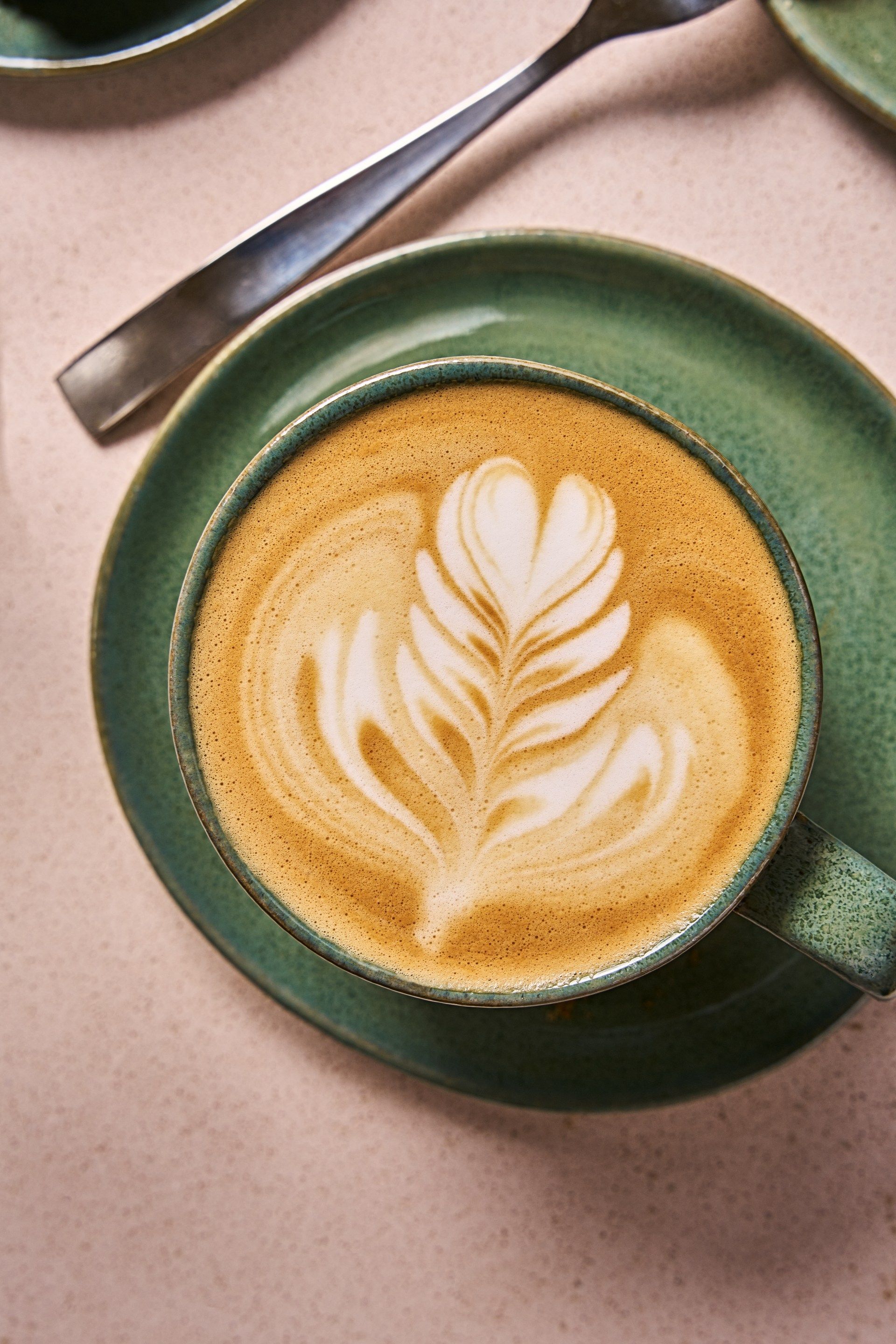 Close-up of a Blue Mountain coffee latte with latte art in a green ceramic cup